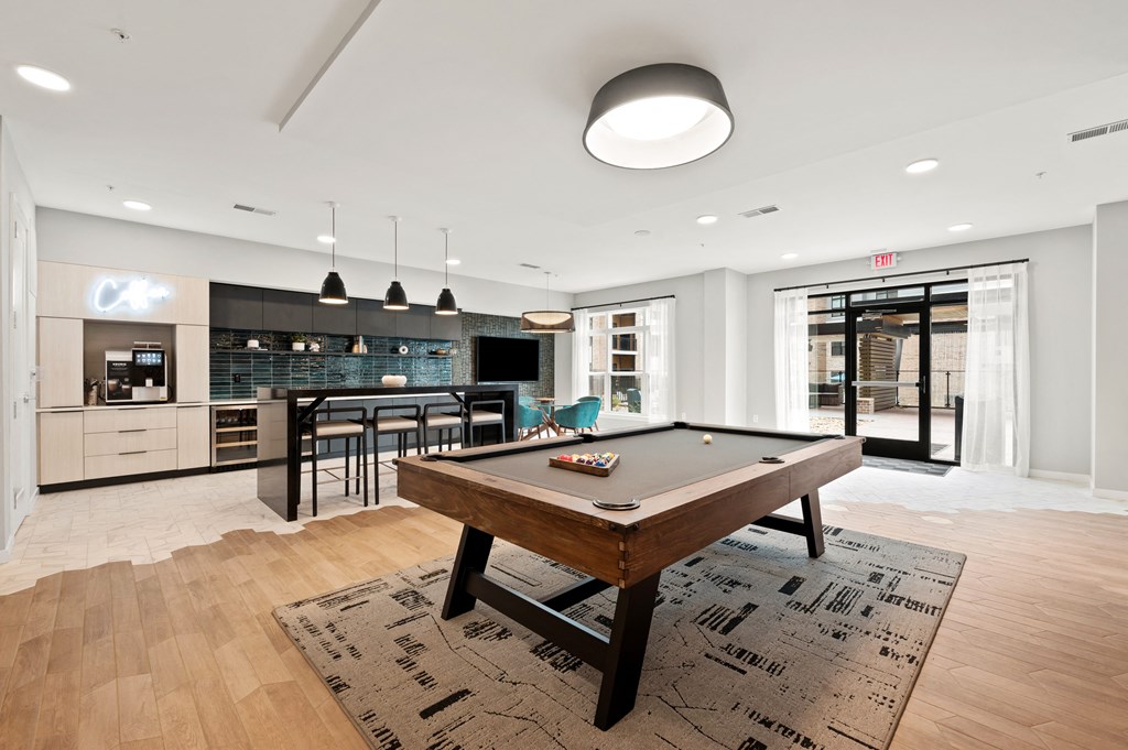 a living room with a pool table and a kitchen with a bar