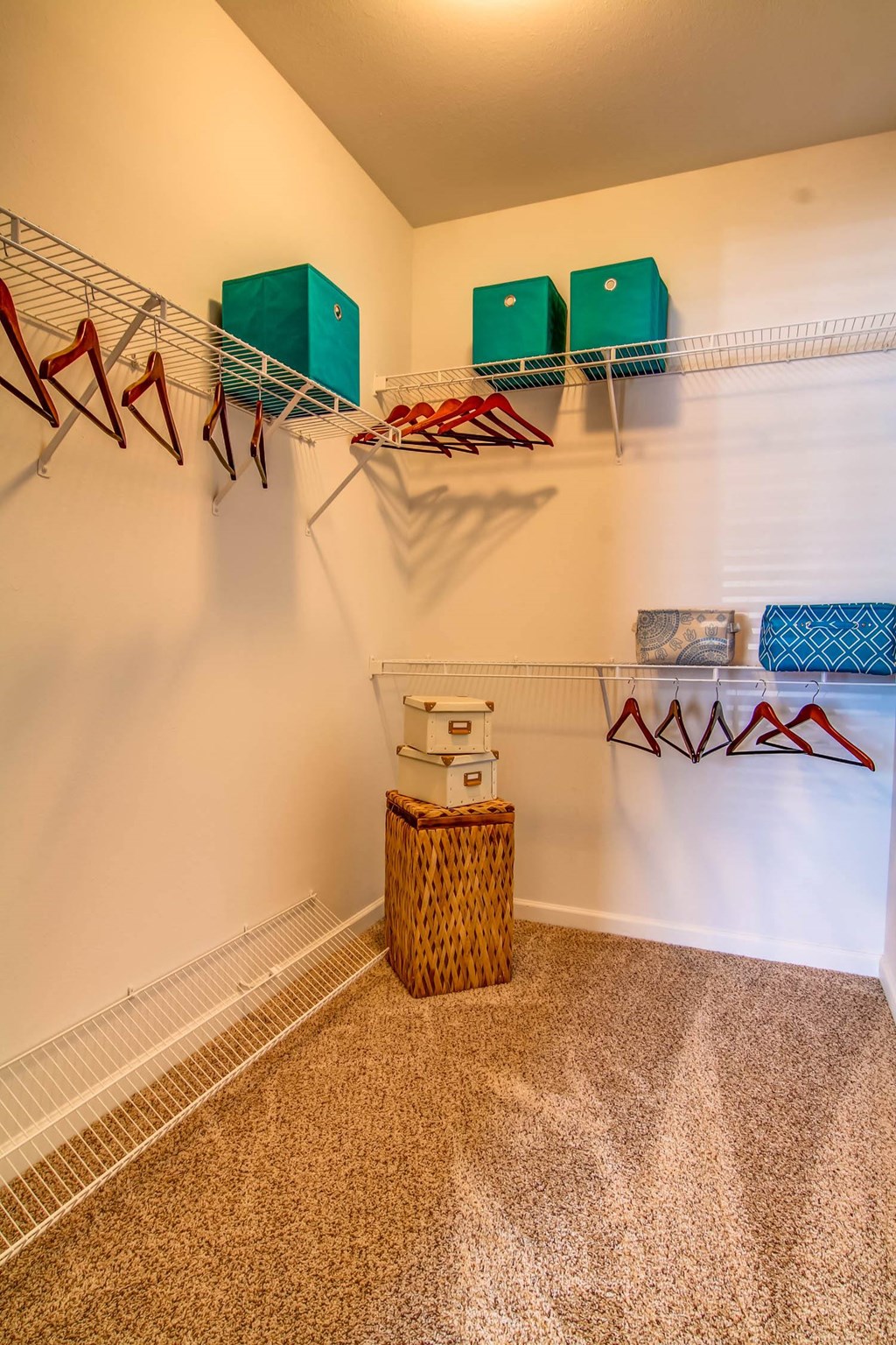 a closet with clothes racks and a basket on the floor