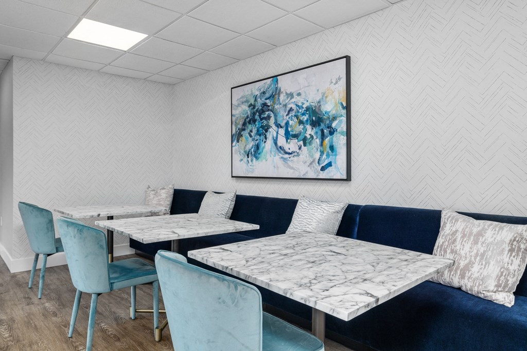 a seating area with blue chairs and white tables with marble tops