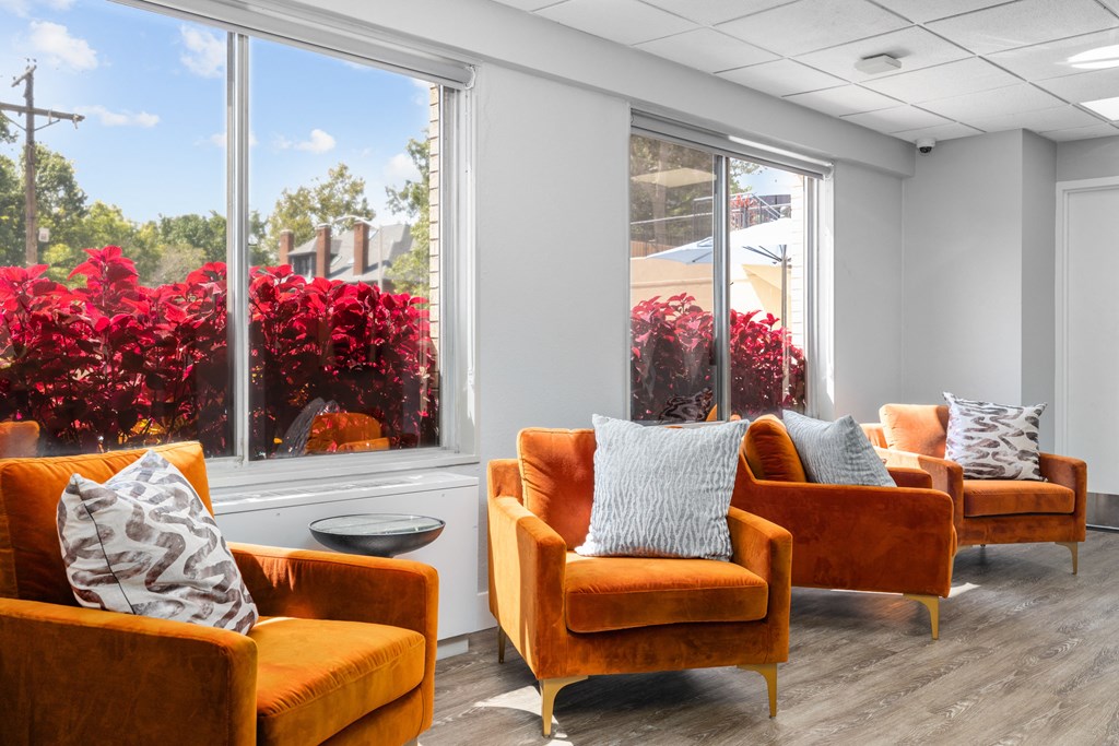 a seating area with orange chairs and red flowers in the background