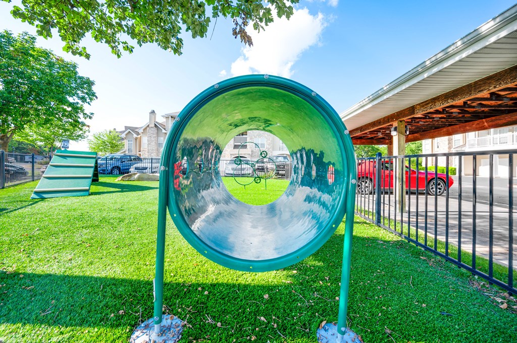 a large metal mirror in a grassy area with a playground in the background