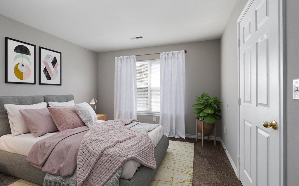 a bedroom with a bed and a plant and white curtains