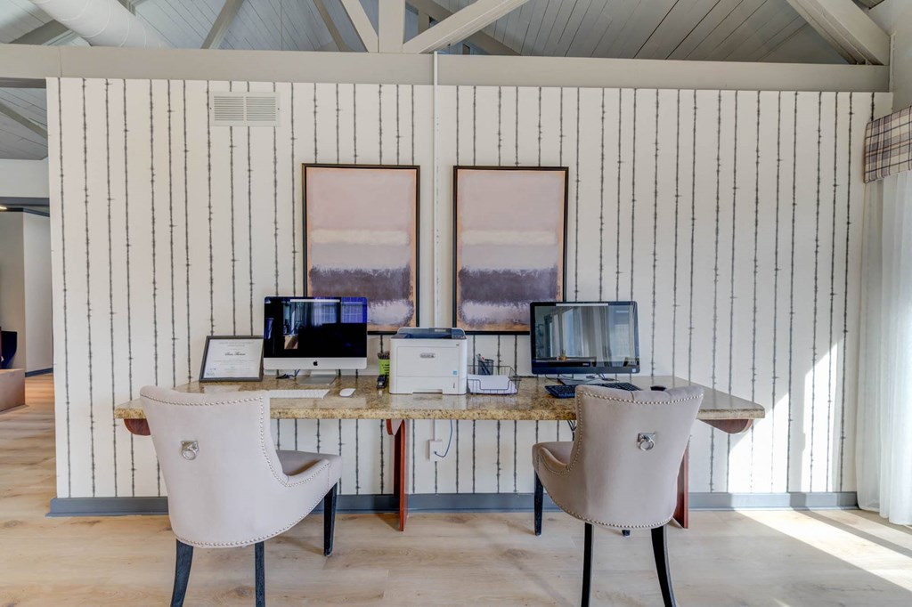 a desk with two chairs and two computers on it