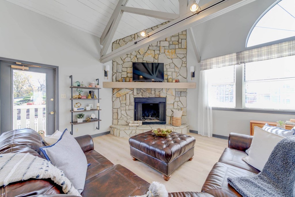 a living room with a stone fireplace and a leather couch