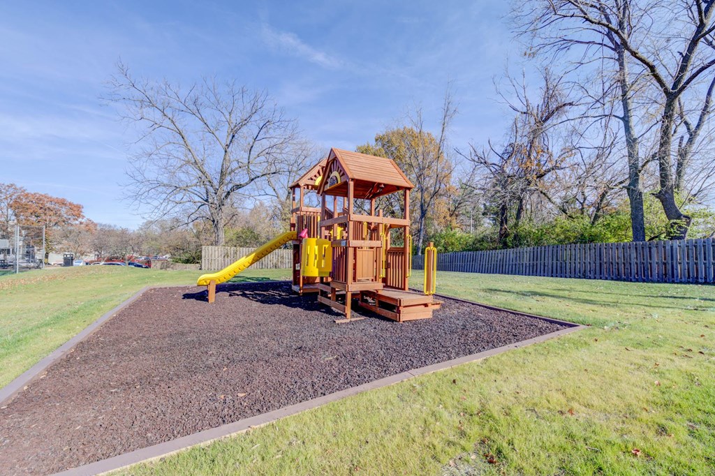 a playground with a yellow swing set in a park