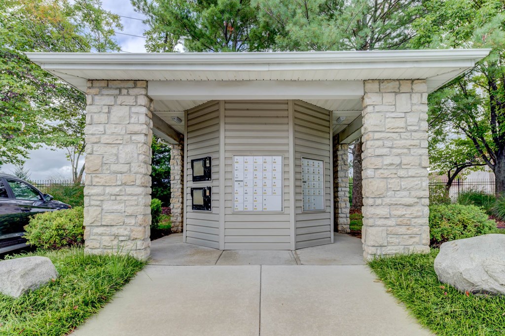 a small tan building with a white roof and stone pillars