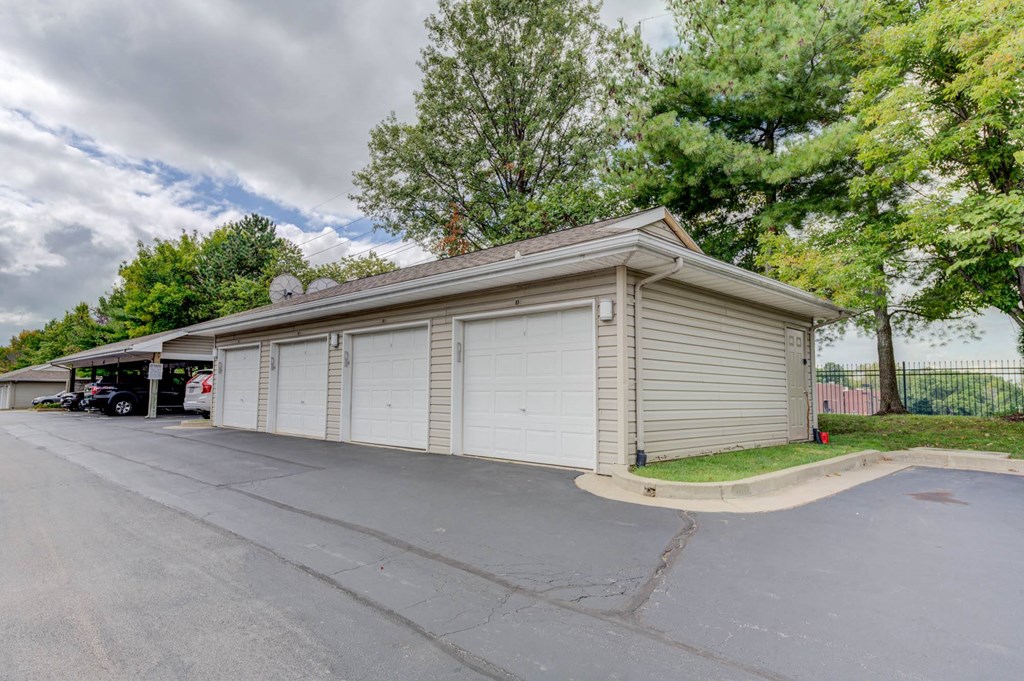 a small garage with a carport and trees in the background