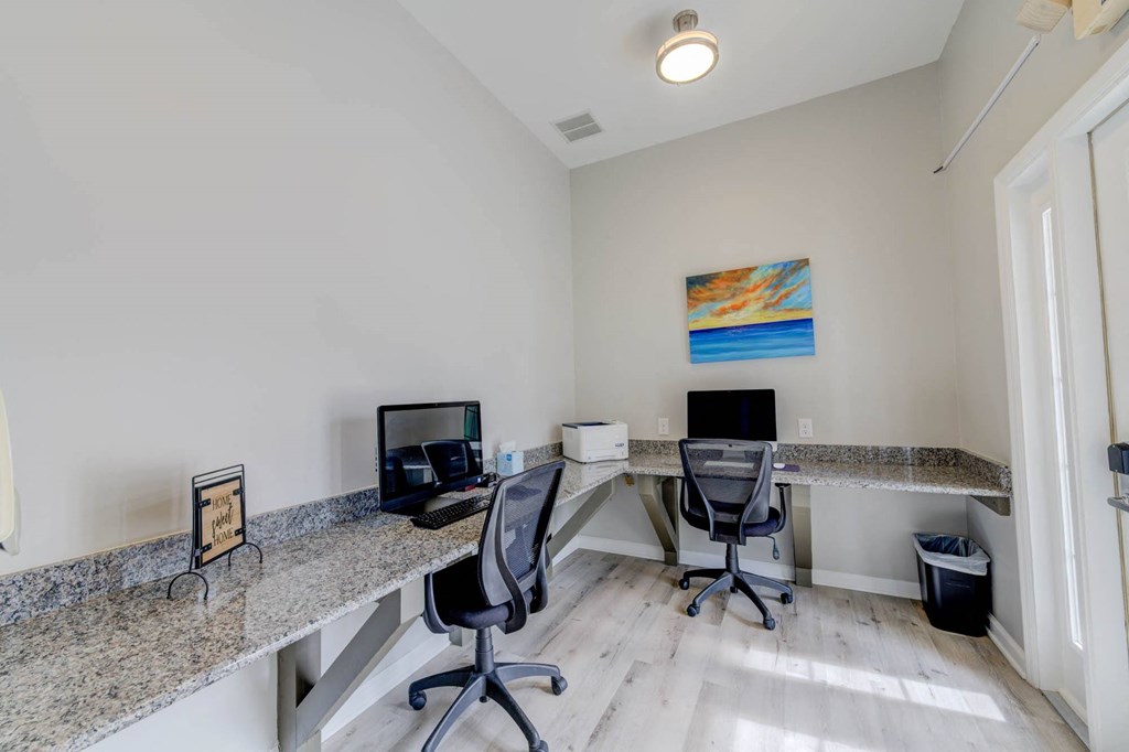 two desks with two computers and two chairs in the corner of a room