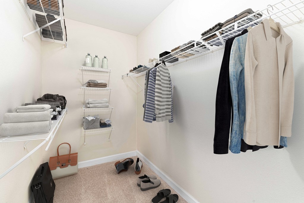 a walk in closet with a rack of clothes and shoes