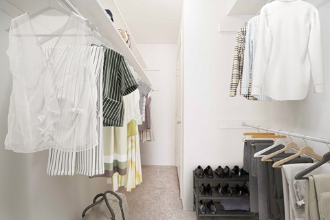 a white closet filled with clothes and shoes