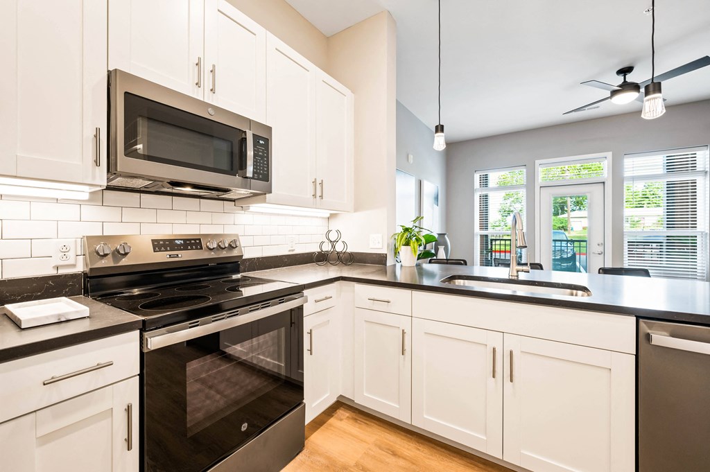 a kitchen with white cabinets and black counter tops and a stove and microwave