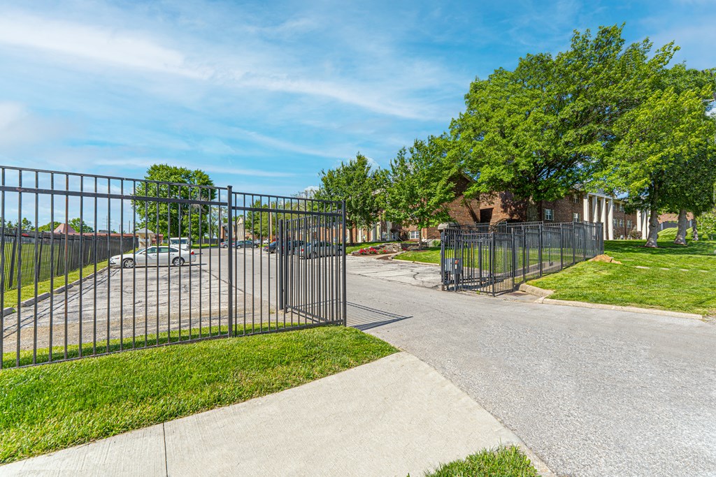 the gate to a playground at the end of a sidewalk