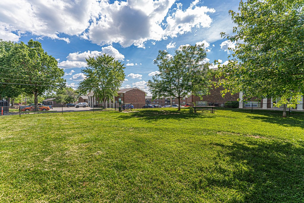 a park with green grass and trees in front of a building