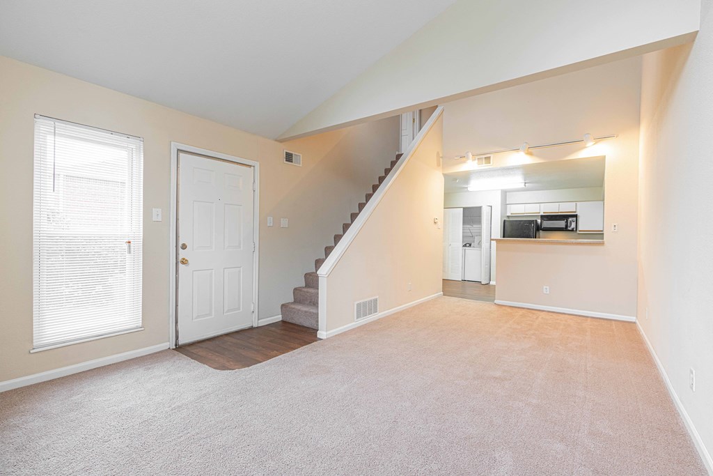 a bedroom with a staircase and a kitchen in the background