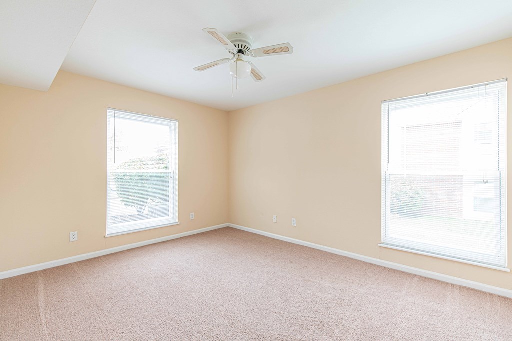 a bedroom with two windows and a ceiling fan
