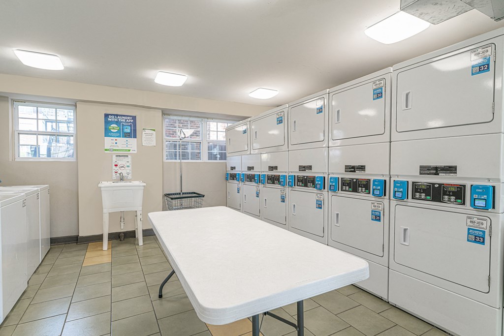 a utility room with a white table in front of a row of white refrigerators