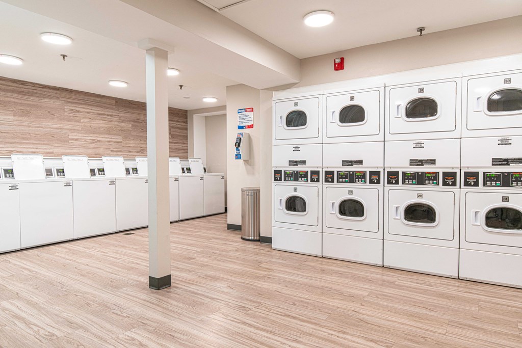 a row of white washers and dryers in a laundry room with a row