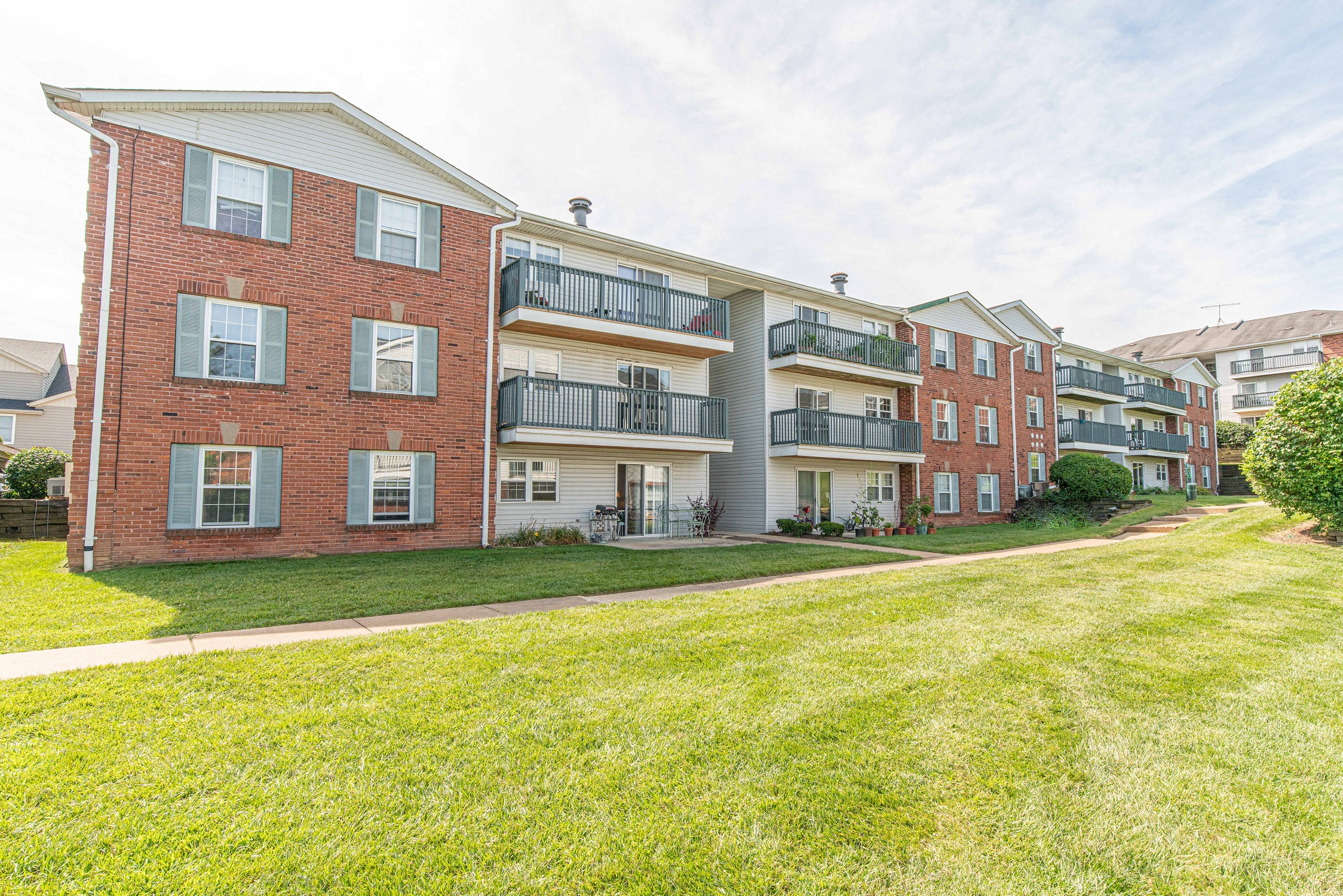 the outlook of a brick apartment building with green grass