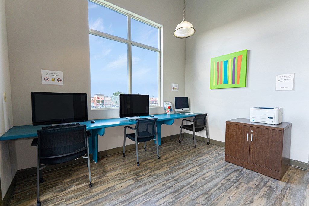 a computer room with two monitors on a desk and a window