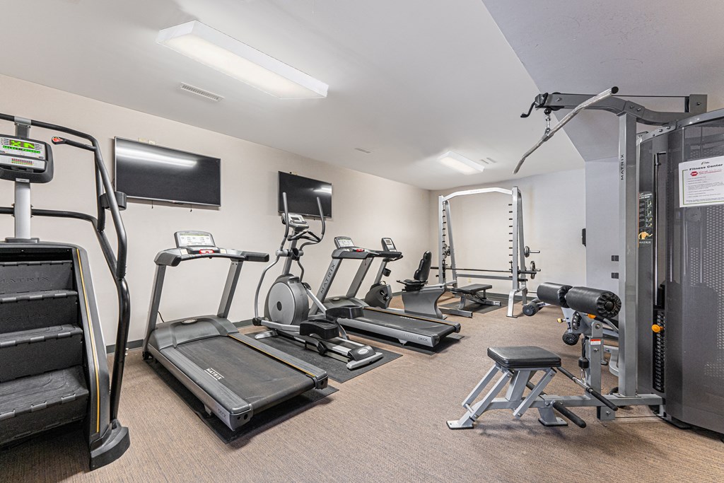 a gym with treadmills and other exercise equipment and a tv