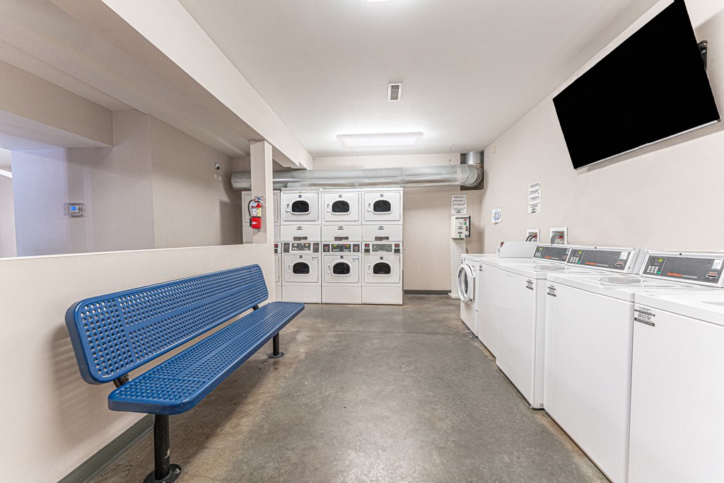 a laundry room with a blue bench and a row of washes and dryers