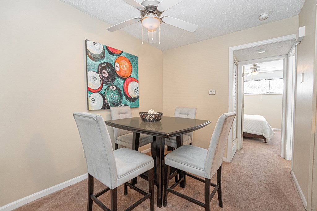 a dining area with a table and chairs and a ceiling fan