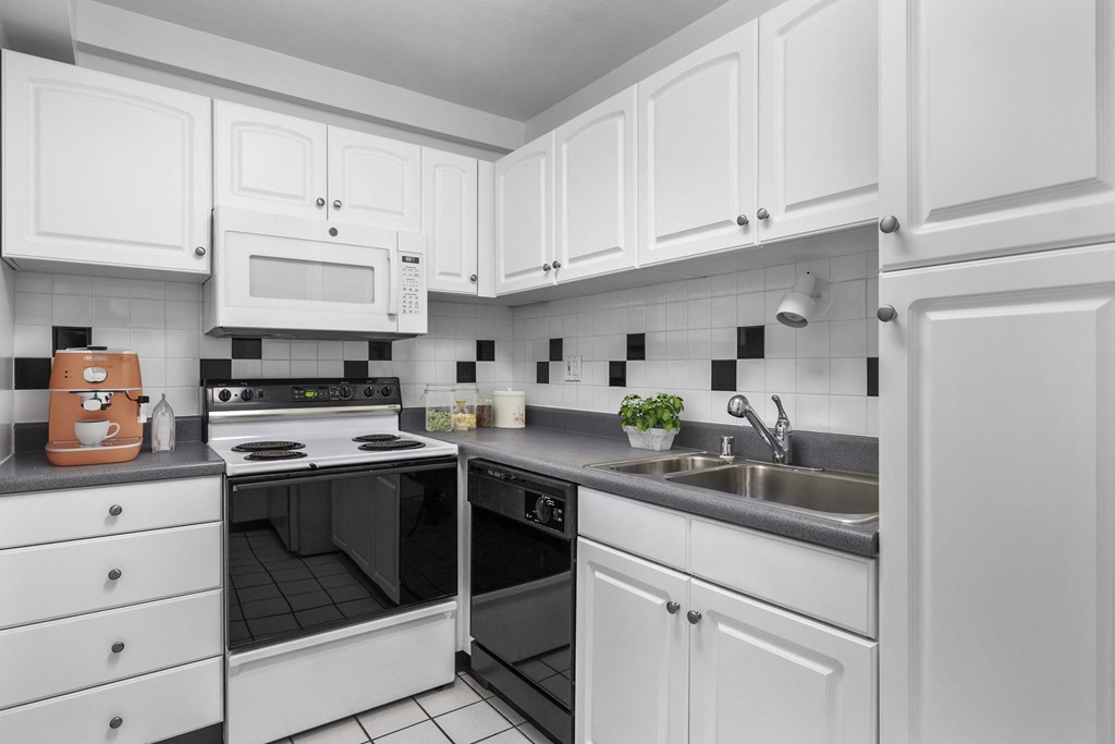 a kitchen with white cabinets and black and white appliances