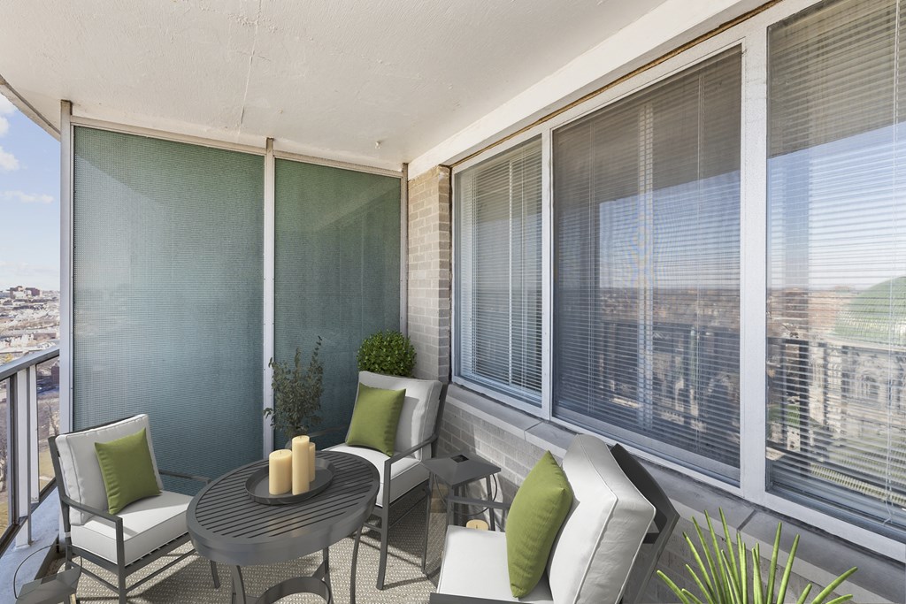 a balcony with a table and chairs and large windows