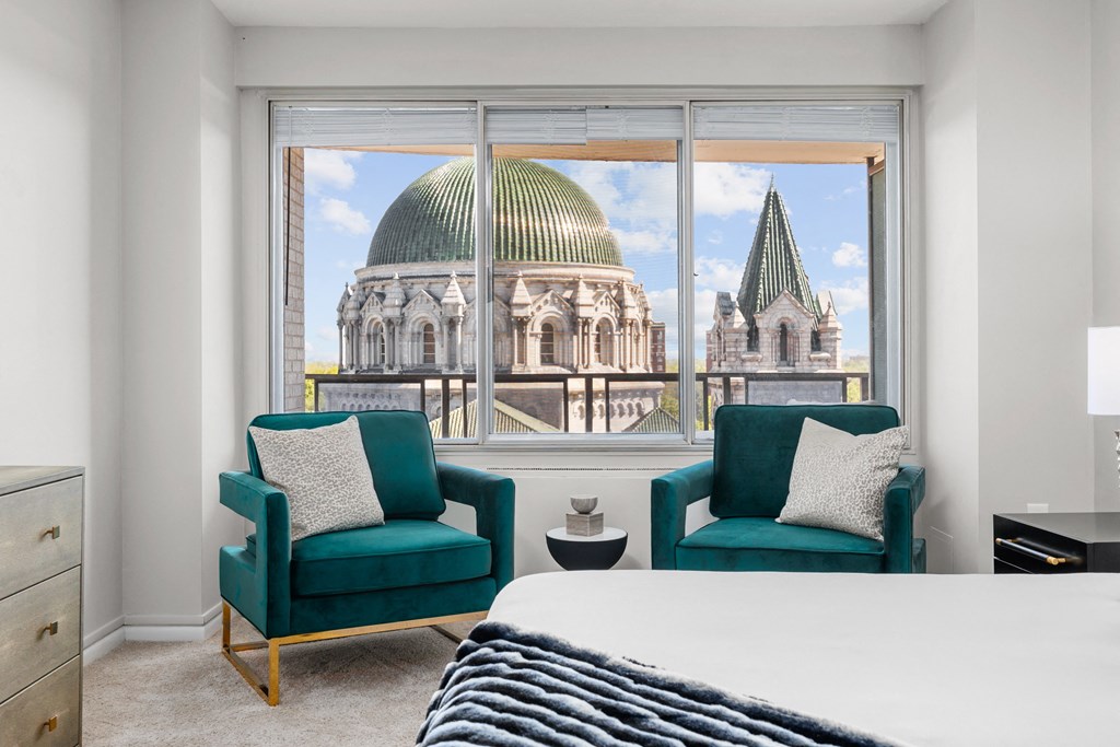 a bedroom with a bed and two chairs in front of a window with a view of a