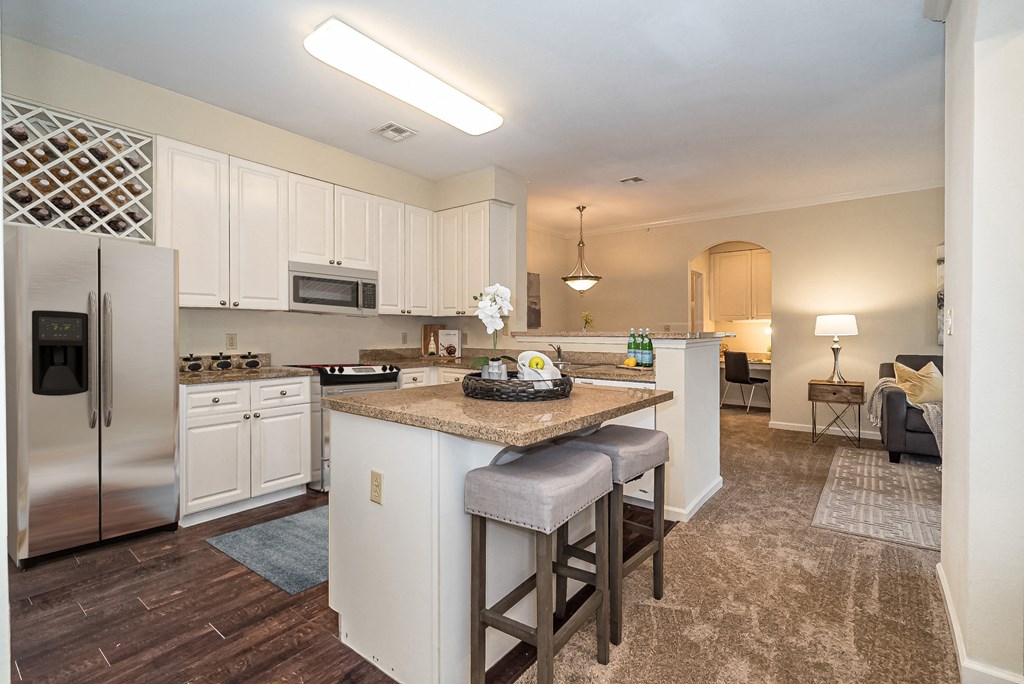 a kitchen with white cabinets and a granite counter top and a island with stools