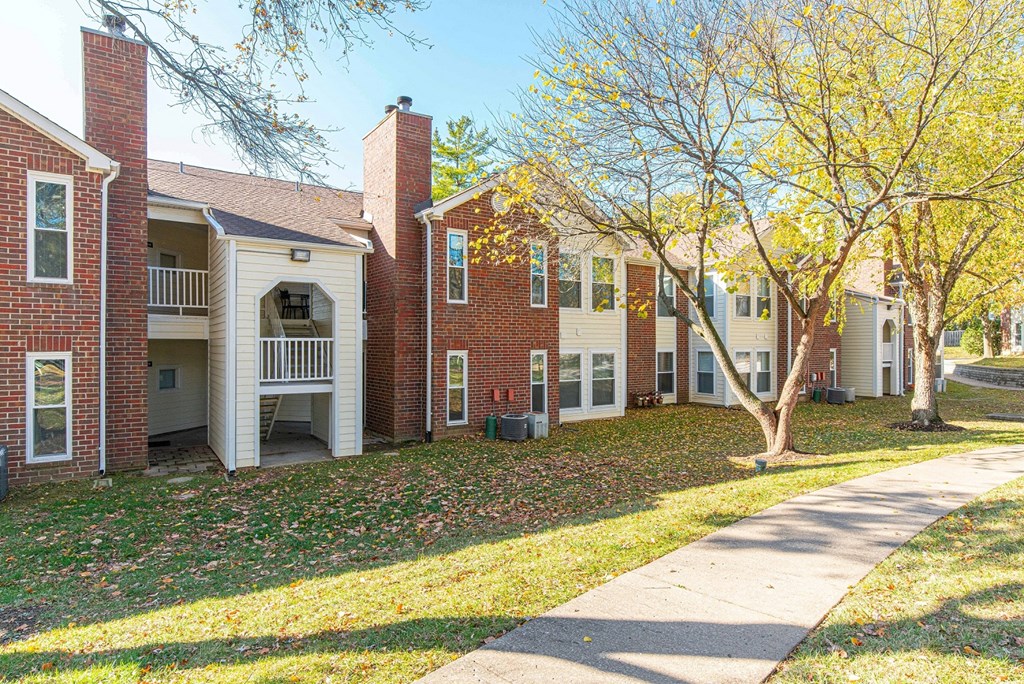 a sidewalk in front of a row of houses with trees