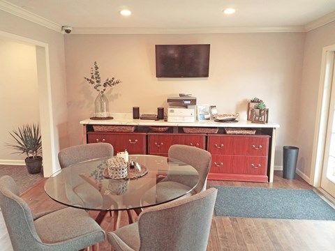 a dining area with a glass table and chairs and a counter with a microwave and