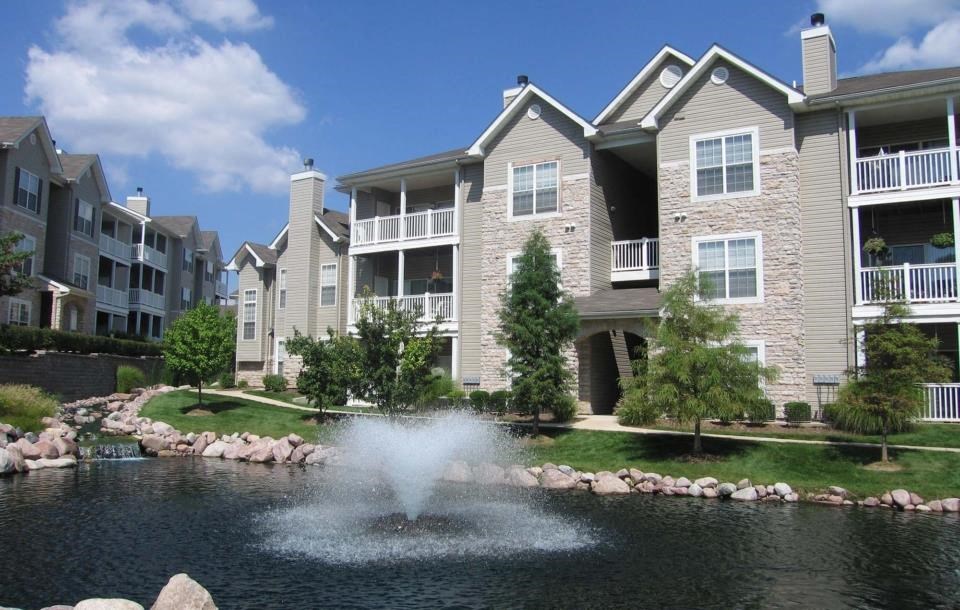 an apartment complex with a fountain in the middle of the yard