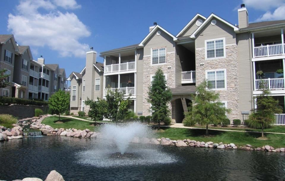 an apartment complex with a fountain in the middle of the yard