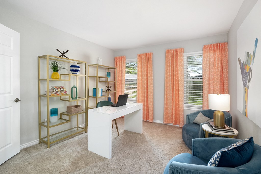 a living room with a desk with a laptop and a couch