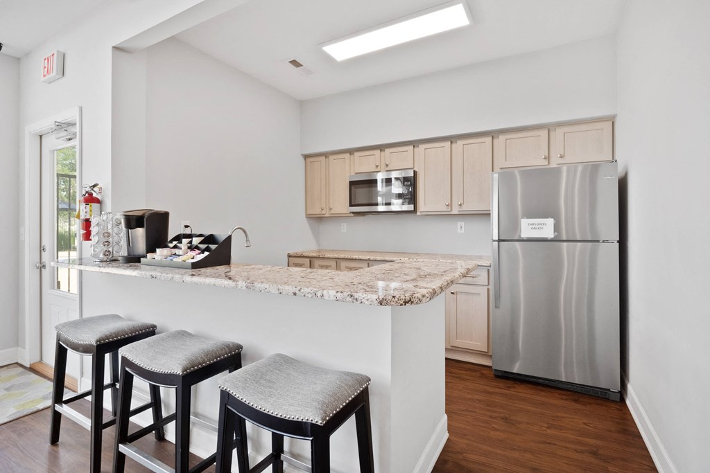 a kitchen with a counter with three stools and a stainless steel refrigerator