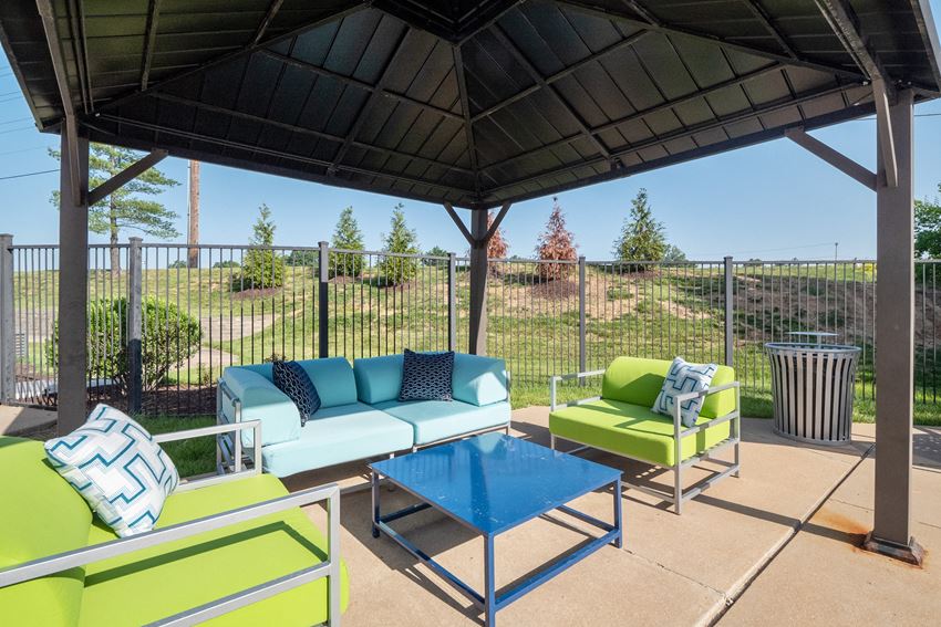 a patio with couches and a table and a gazebo