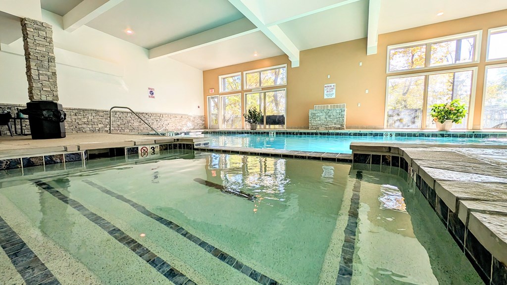 the indoor pool is heated and has large windows and a water feature