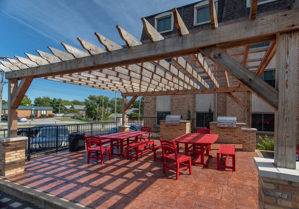 a patio with a table and chairs under a wooden roof