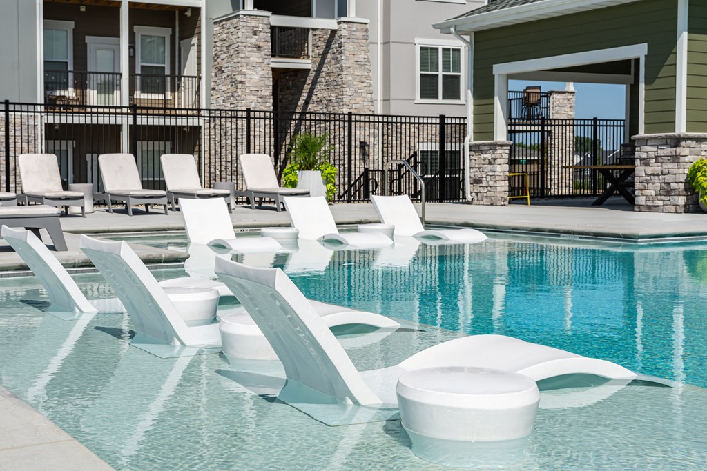 a swimming pool with white lounge chairs and a house in the background