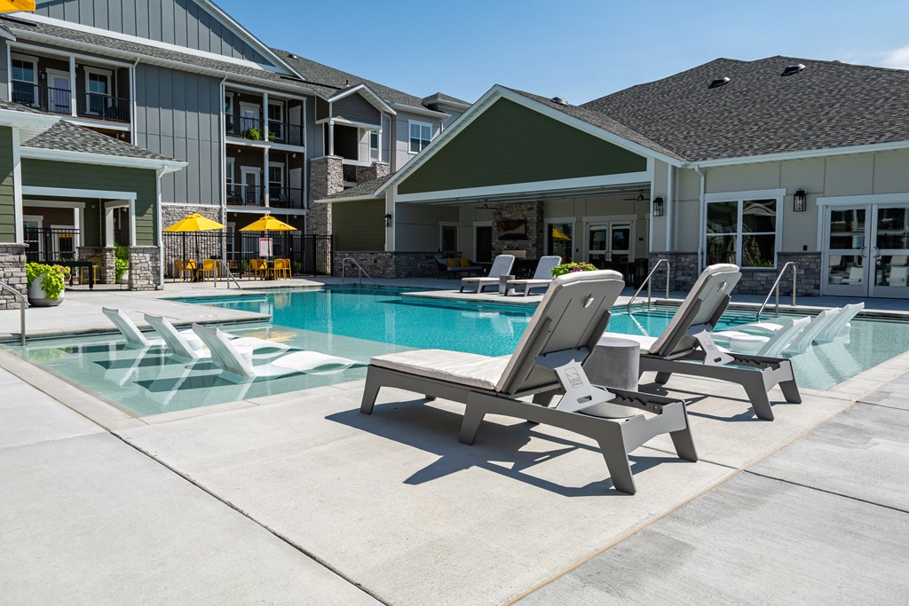a swimming pool with chaise lounge chairs and a building in the background