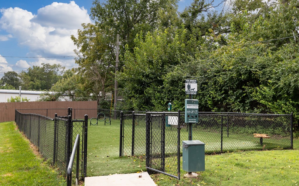 a chain link fence surrounds a park with a tennis court