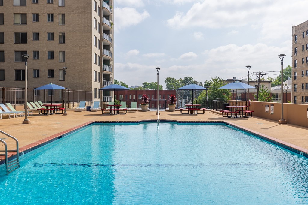 a swimming pool with tables and umbrellas in front of a building