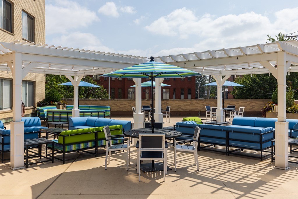 a patio with blue couches and green couches under a white pergola