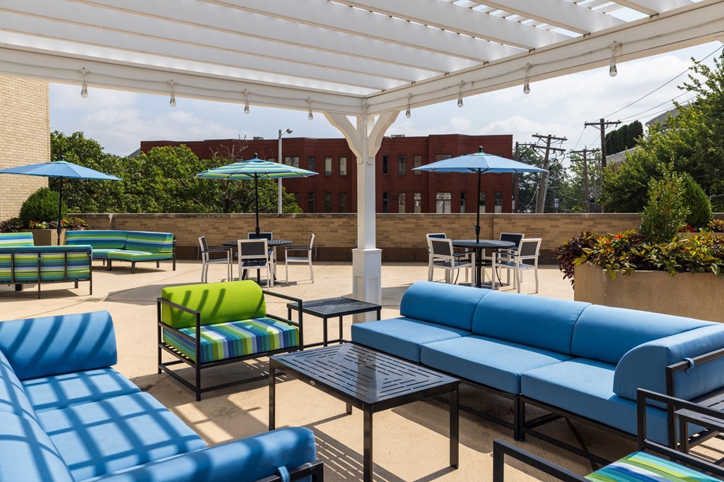 a patio with blue couches and green and blue chairs and umbrellas
