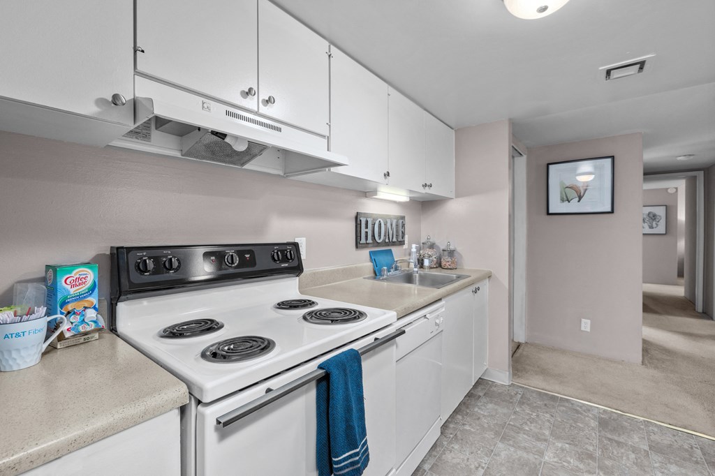 a kitchen with white appliances and white cabinets and a sink