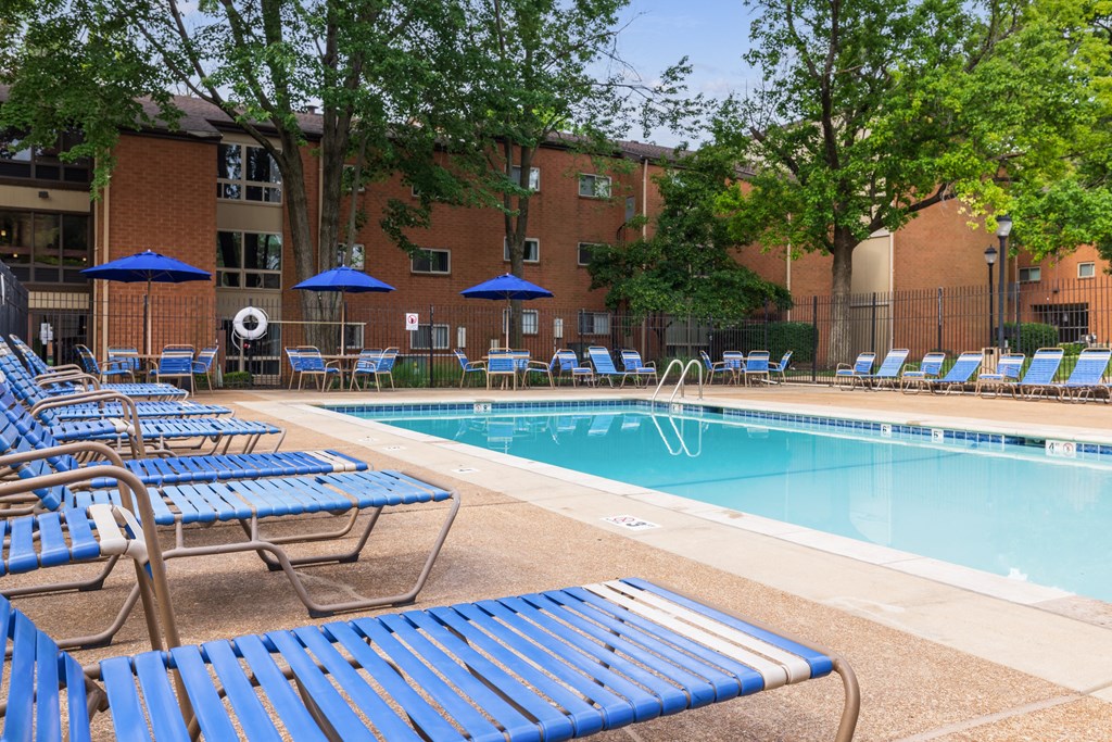 a swimming pool with chaise lounge chairs and umbrellas in front of a brick building