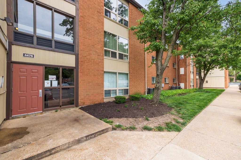 a front entrance to a brick building with a tree in the front yard
