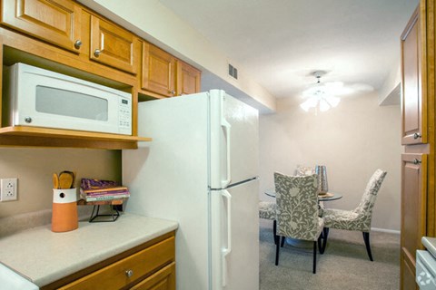 a kitchen with a refrigerator and microwave and a dining room with a table and chairs