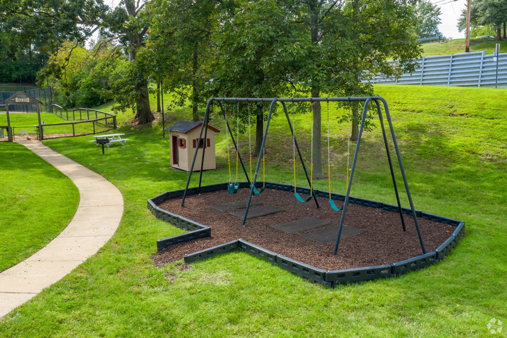 a swing set in a park with a bird house